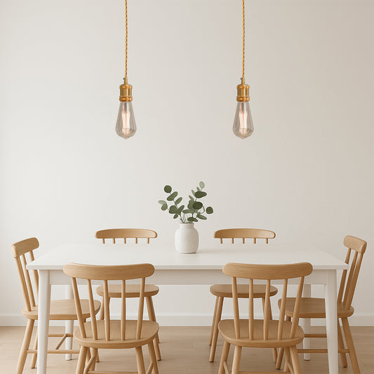 Two French gold pendant lights with twisted fabric cables and bulbs, hanging above a dining table