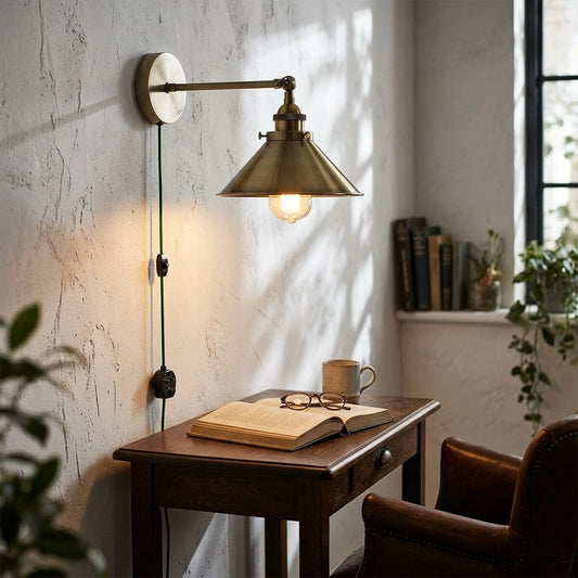 Wall-mounted lamp illuminating a desk with an open book and mug in a cozy room.