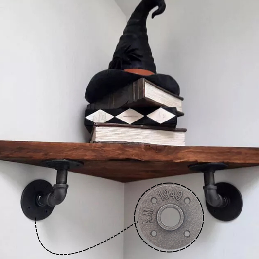 Wooden shelf with black pipe brackets and a witch hat on books against a white wall.