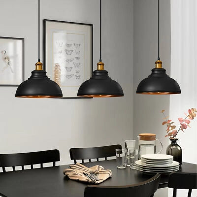 Three black pendant lights hanging above a dining table with decor items.