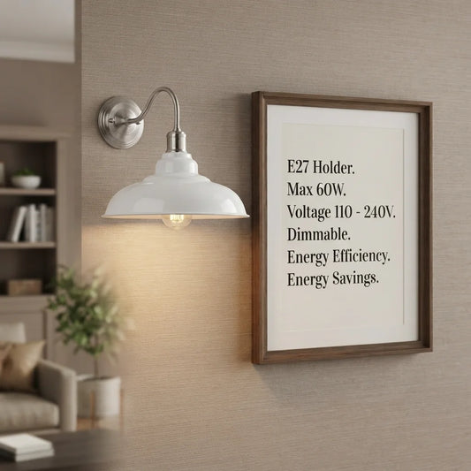 A wall-mounted sconce with a white dome shade and silver metal arm, shown lit on a beige textured wall next to a framed text print.