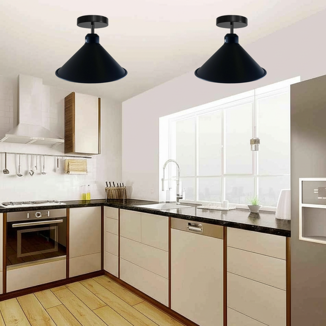 Two industrial-style black cone shade flush mount ceiling light fixtures illuminate a modern kitchen with white cabinetry, dark counter-tops, and a large window.