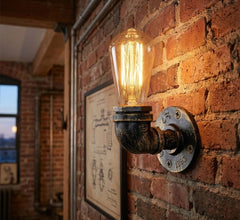 Industrial-style wall sconce with a glowing filament light bulb mounted on a brick wall.