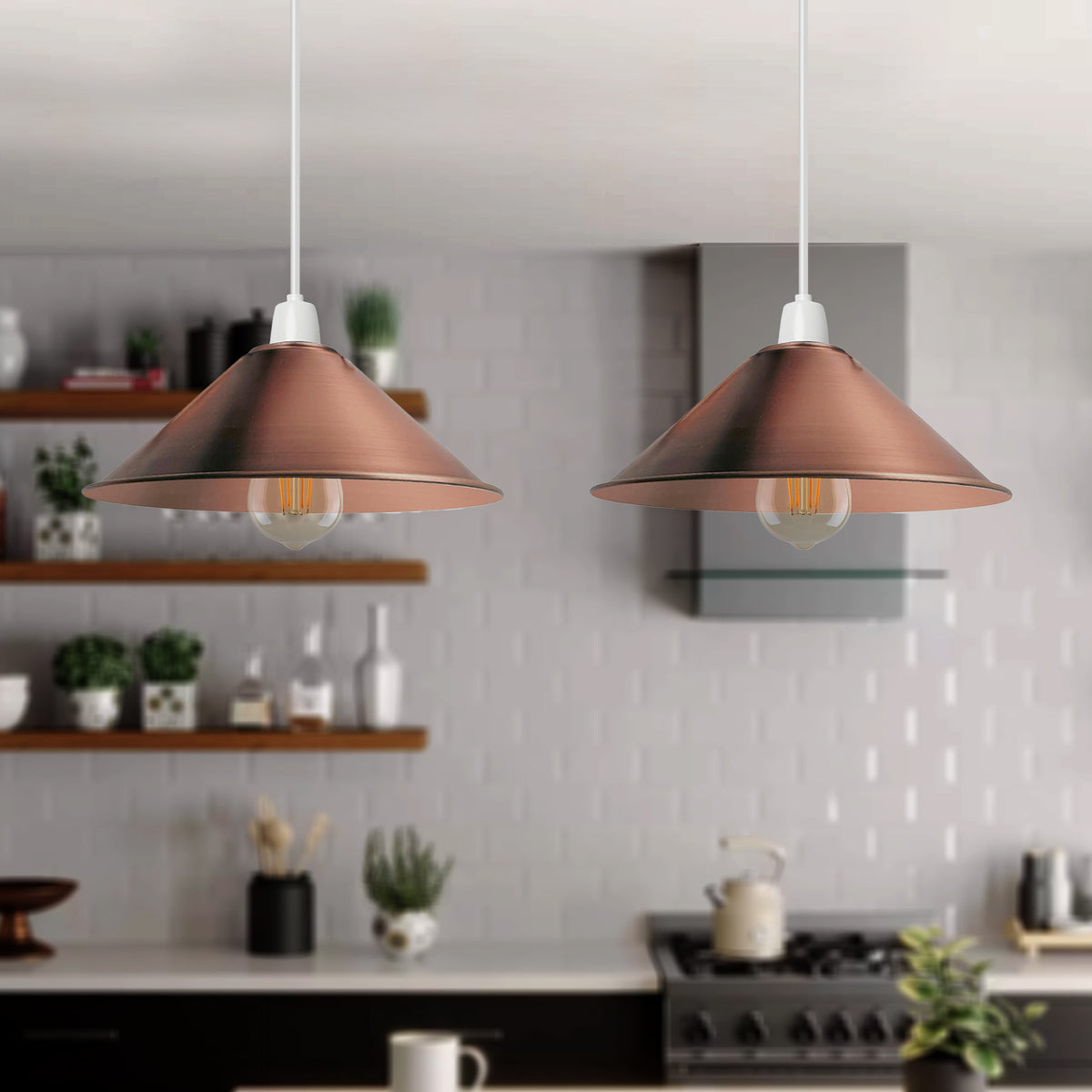 Two copper-finished pendant light shades hanging in a modern kitchen setting, with white cords and visible bulb filaments.