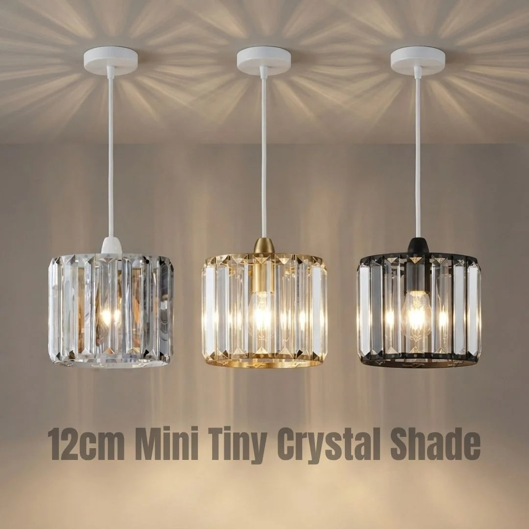 Three mini crystal pendant light shades hanging from white ceiling canopies, shown illuminated against a warm beige wall. The shades are clear, silver-toned, and black, with the text '12cm Mini Tiny Crystal Shade' at the bottom.
