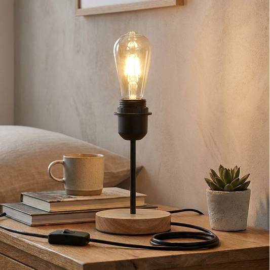 Table lamp with a lit bulb on a wooden nightstand in a bedroom setting.