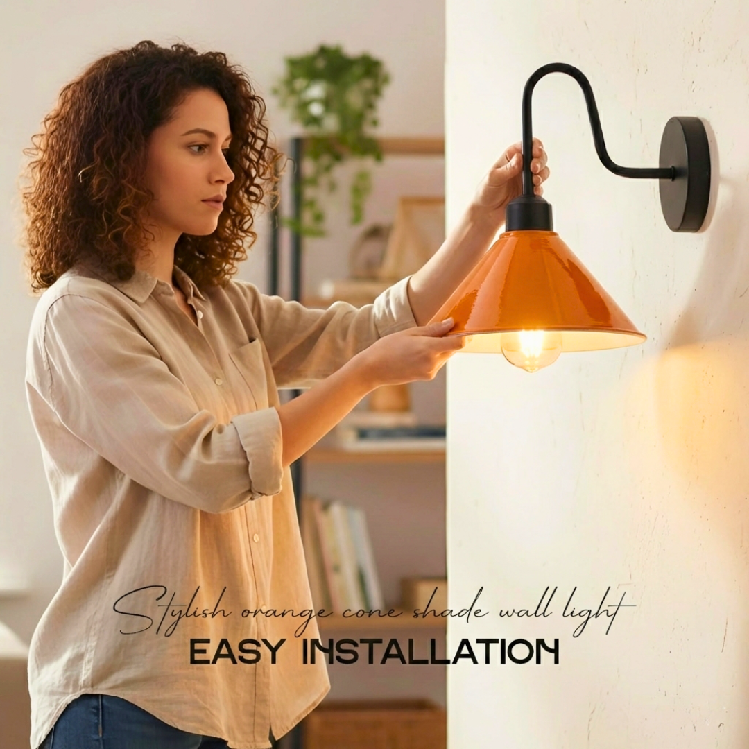 Woman installing a stylish orange cone shade wall light in a home setting.