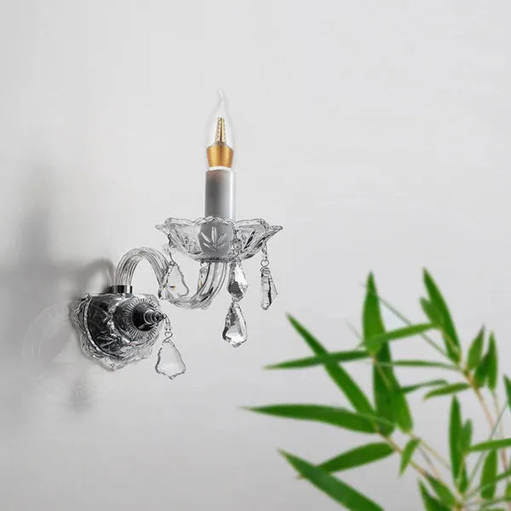 LED candle bulb in a crystal wall light beside a plant