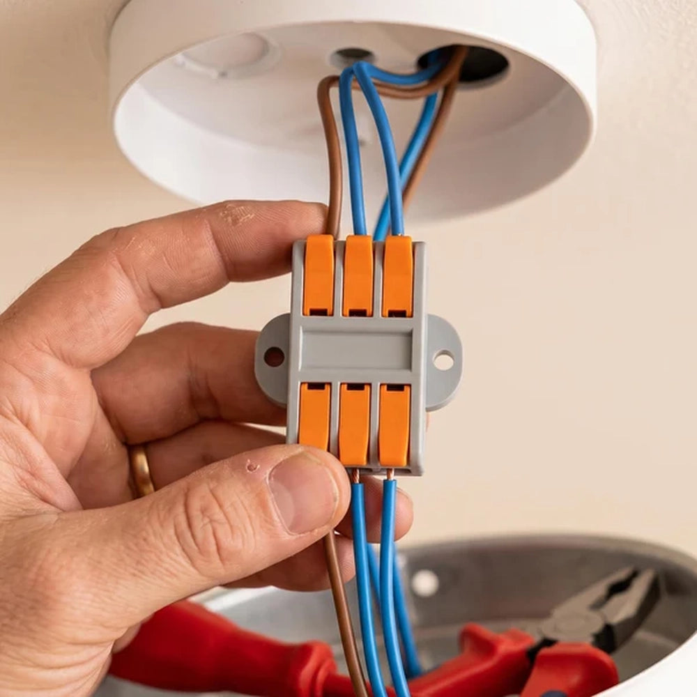hand holding a lever wire connector joining cables at a ceiling light