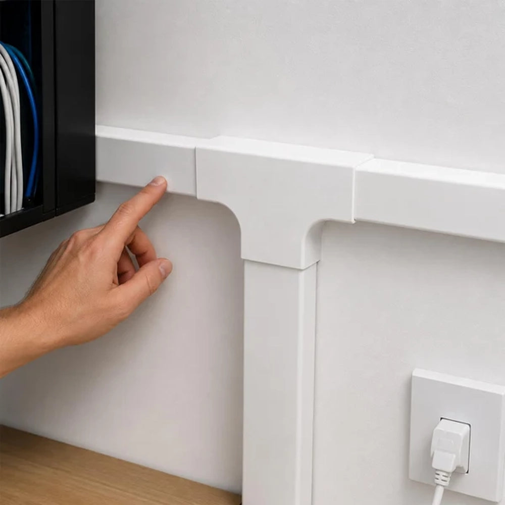 hand pointing at a white trunking T-junction above a wall socket